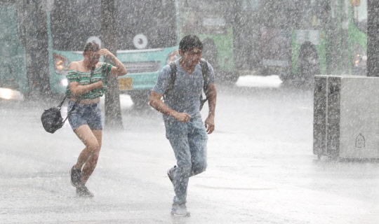 반갑지만...일단 뛰어!  폭염이 계속된 28일 서울 광화문 광장 주변에 한때 강한 소나기가 내리자 시민들이 비를 피하기 위해 뛰고 있다.